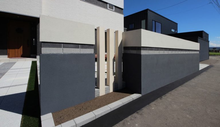 白とダークグレーで統一された建物と調和した門塀