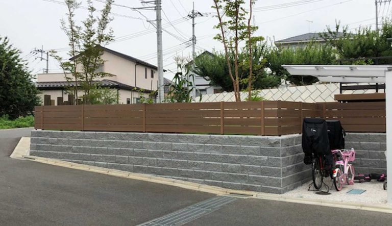 白い住宅を引き立てる石垣ブロックと木フェンス
