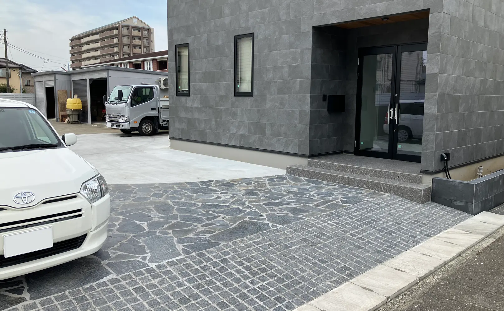 建物の外壁と合わせた黒色の天然石アプローチ