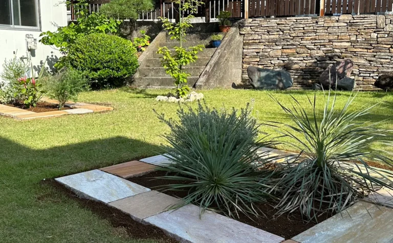 明るい平板で囲った芝生のお庭の花壇
